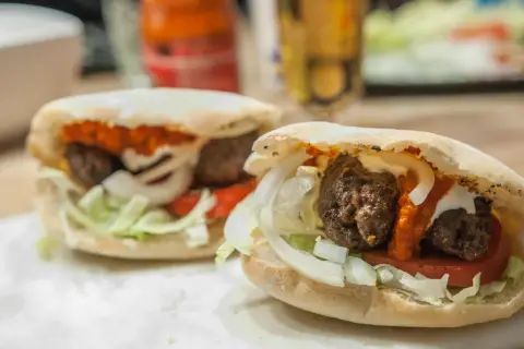 Två saftiga cevapcici i pitabröd med lök, tomat och sås. Perfekt för en snabb och god måltid, som ett enkelt cevapcici recept.