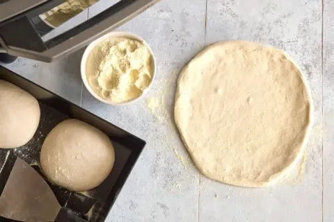 Förberedelser för pizza: poolish pizzadeg, mjöl i skål och degbollar i form.