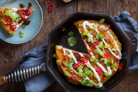 En saftig okonomiyaki i gjutjärnspanna, toppad med gräddfil, salladslök och chili. Ett perfekt recept för en smakrik middag.