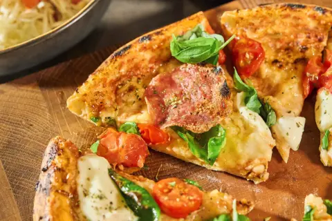 Krispig pizzadeg som på pizzeria, med salami, tomater och basilika. En härlig syn för ögat!