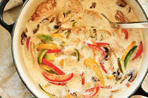 En krämig kycklinggryta med ris, full av färgglada paprikor och champinjoner i en smakrik sås.