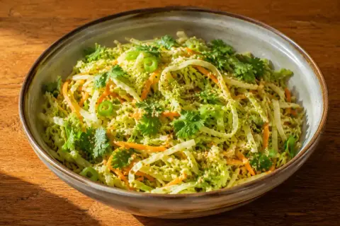 En skål med fräsch asiatisk kålsallad med strimlad kål, morötter, koriander och sesamfrön.