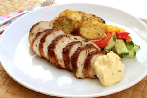 Skivad kycklingfilé, perfekt grillad, serveras med potatis, grönsaker och en klick krämig sås. En härlig måltid!