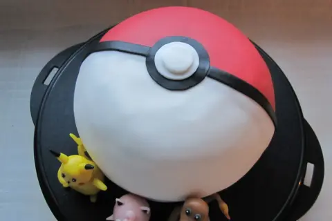 En pokemon tårta formad som en pokéboll med Pikachu, Jigglypuff och Charmander.