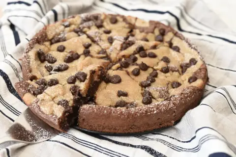 En kladdkaka med cookie dough och chokladbitar, pudrad med florsocker. En bit är uppskuren.