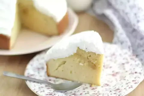 En saftig bit tres leches-kaka med fluffig vit topping, serverad på en blommig tallrik med en sked.