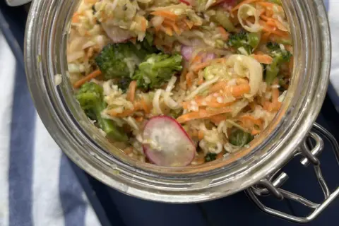 En burk med färgglad 3 veckors sallad, full av krispig kål, morötter, broccoli och rädisor. Perfekt för en hälsosam lunch.