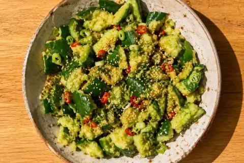 En skål med asiatisk gurksallad, toppad med sesamfrön, chili och salladslök. En fräsch och smakrik rätt.