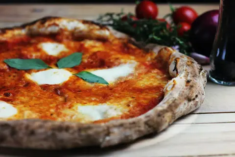 En nybakad pizza med mozzarella och basilika, perfekt för en mysig kväll med din pizzasten från Biltema.
