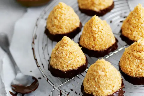 Kokostoppar recept: konfekt med kokos och choklad på ett galler. En sked med choklad ligger bredvid.