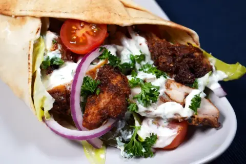 En saftig kyckling shawarma i pitabröd med tomater, lök, sallad och vit sås.