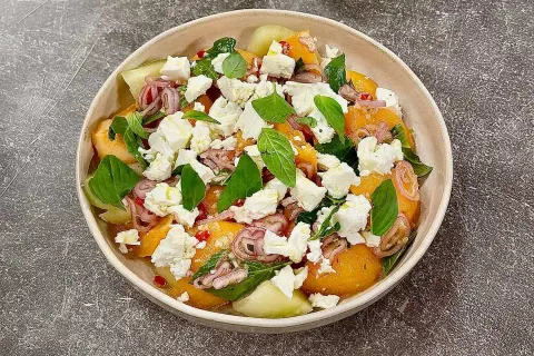 En uppfriskande melon och fetaostsallad med basilika och rödlök. Perfekt sommarbuffé.