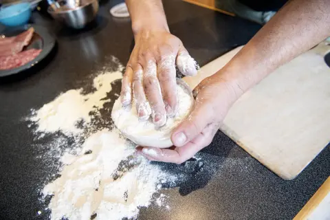 Händer som knådar deg med mjöl för en äkta neapel pizza.