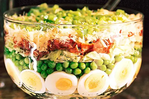 Lager på lager i en glasskål: ägg, gröna ärtor, sallad, bacon, ost och paprika. Ett härligt sallad recept!