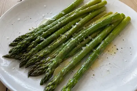 En tallrik med nykokt sparris, lätt smörad och strödd med flingsalt och peppar. Perfekt för att koka sparris!