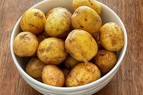 En skål med färskpotatis, redo att koka med eller utan lock. Perfekt för en svensk sommarmåltid.