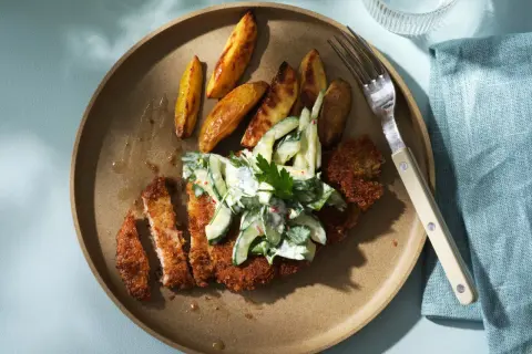 Krispigt schnitzel recept med klyftpotatis och krämig gurksallad. En perfekt middag!