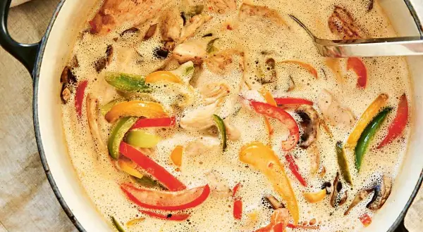 En krämig kycklinggryta med ris, full av färgglada paprikor och champinjoner i en smakrik sås.