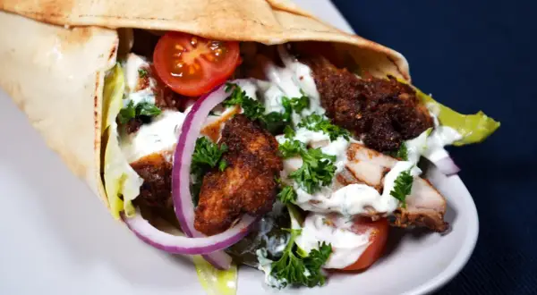 En saftig kyckling shawarma i pitabröd med tomater, lök, sallad och vit sås.