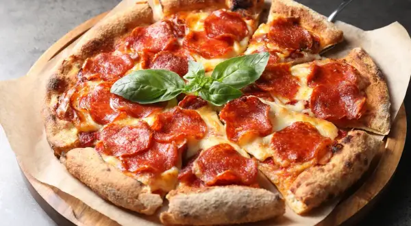 En napolitansk pizza med generöst med pepperoni som topping, toppad med färsk basilika.