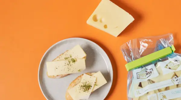 Ostskivor på bröd och en bit ost. En påse med ostbitar visar att man kan frysa ost för att bevara den.