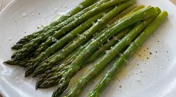 En tallrik med nykokt sparris, lätt smörad och strödd med flingsalt och peppar. Perfekt för att koka sparris!