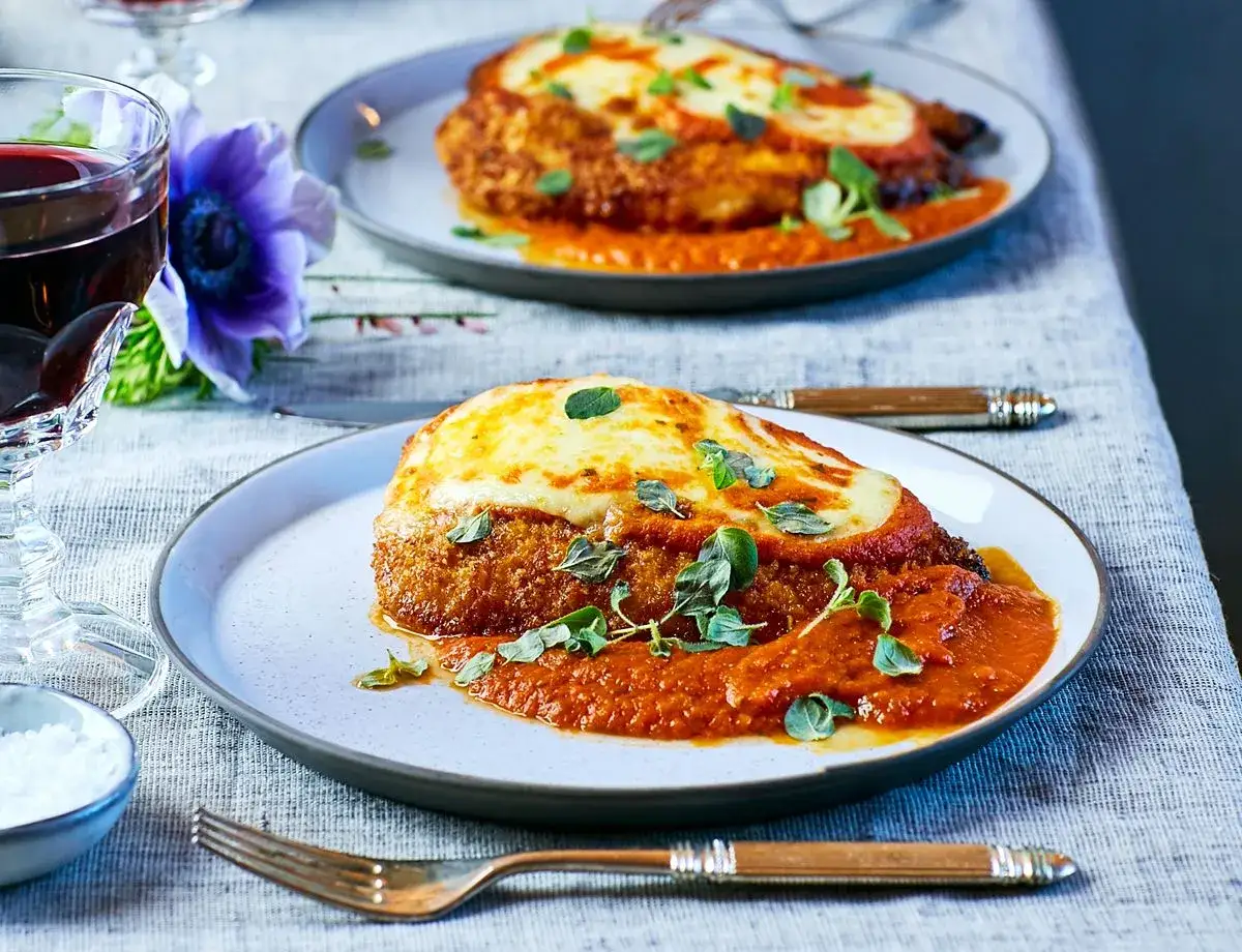 Tv&aring; tallrikar med kycklingparmesan, t&auml;ckt med tomats&aring;s och sm&auml;lt ost. Den dubbla paneringen ger en h&auml;rlig krispighet.